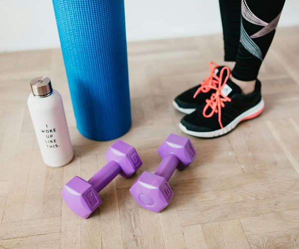 Set of simple home workout equipment like a mat and dumbbells.